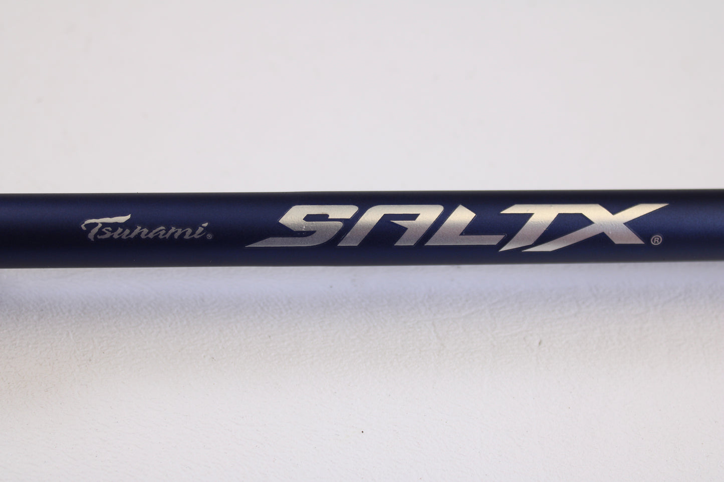 Close-up of the Tsunami SaltX Surf TSSTXIISS872M 8'7" Medium 2 Piece used spinning rod in excellent condition, shown against a white background. Trade in your gear through our Rod and Reel Trade-In Program for store credit.