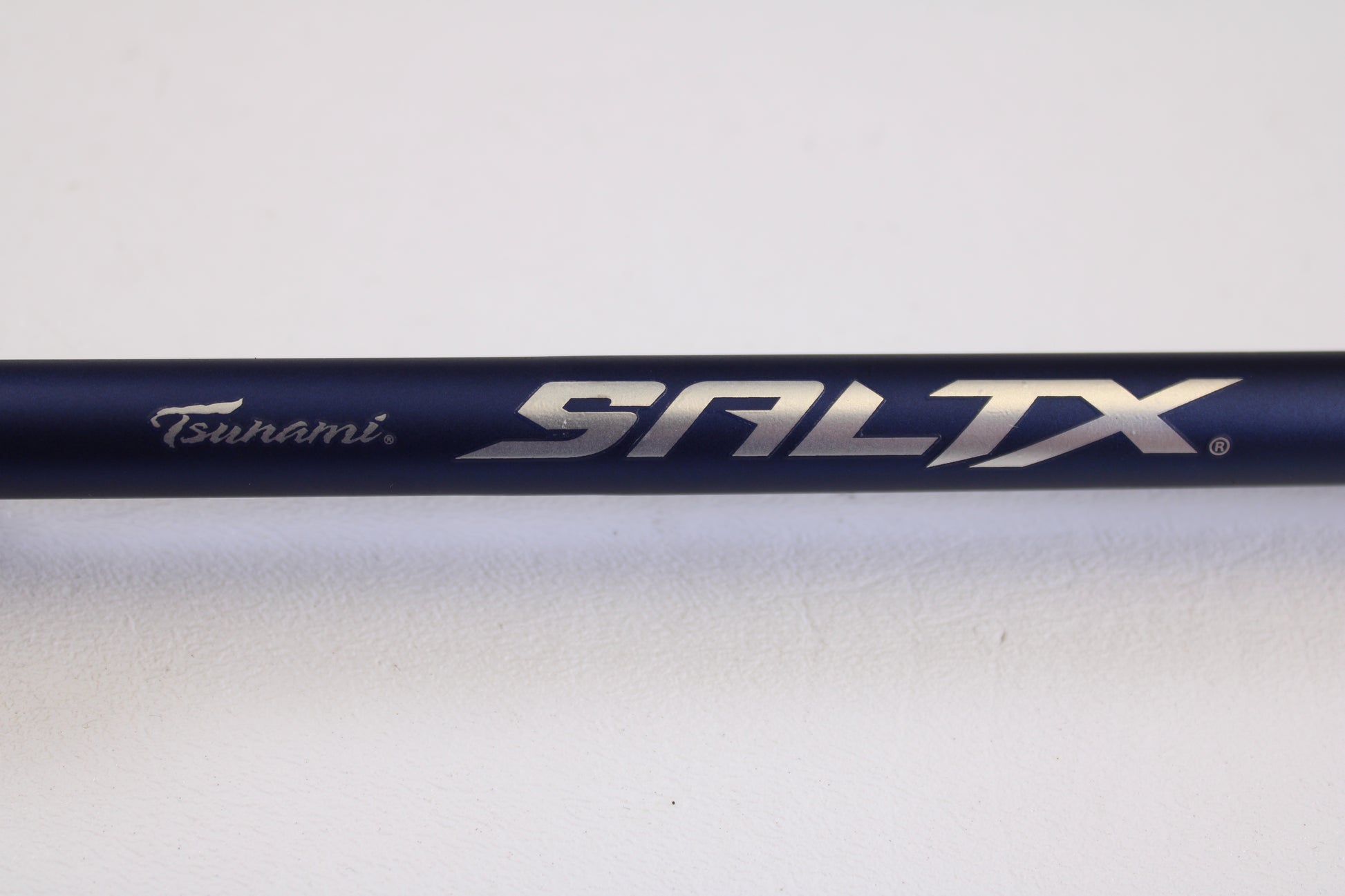 Close-up of the Tsunami SaltX Surf TSSTXIISS872M 8'7" Medium 2 Piece used spinning rod in excellent condition, shown against a white background. Trade in your gear through our Rod and Reel Trade-In Program for store credit.