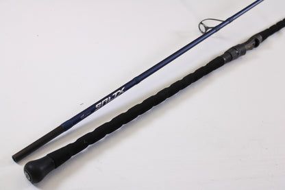 A close-up of the Tsunami SaltX Surf TSSTXIISS771M 7'7" Medium 1 Piece Used Spinning Rod in excellent condition, featuring a black foam handle and blue shaft—ideal for upgrading through our Rod and Reel Trade-In Program.