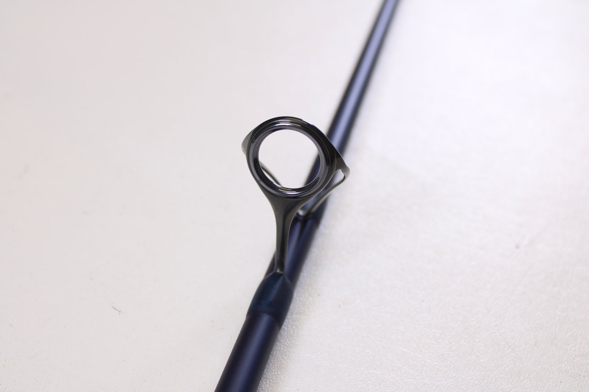 Close-up of the Tsunami SaltX Surf TSSTXIISS771M 7'7" medium used spinning rod in excellent condition, highlighting its blue color and metal guide—ideal for those interested in our Rod and Reel Trade-In Program.