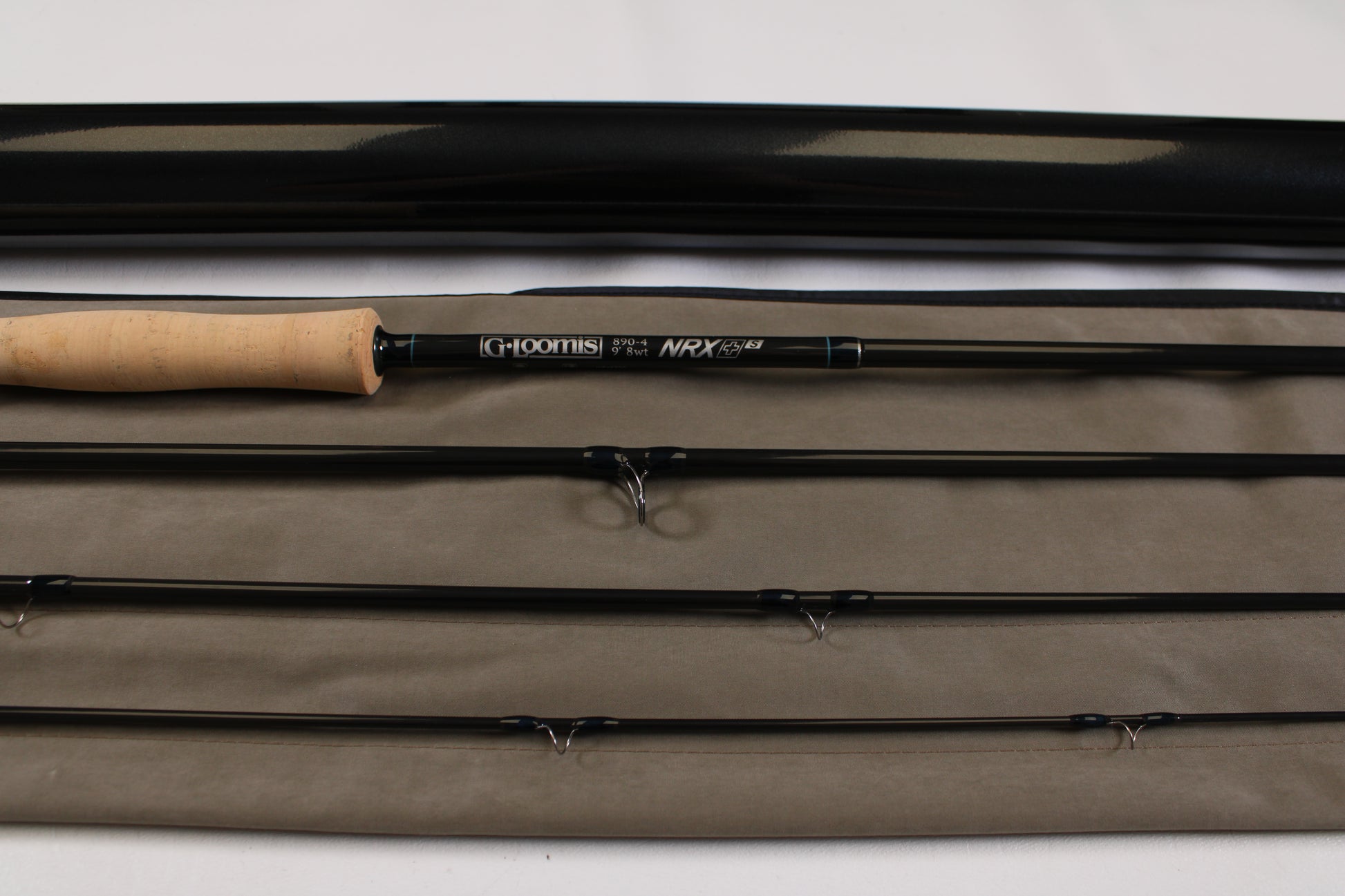 A G. Loomis NRX+ S 890-4 Used Fly Rod in mint condition is displayed with its cork handle, black protective case, and rod sleeve on a light surface.