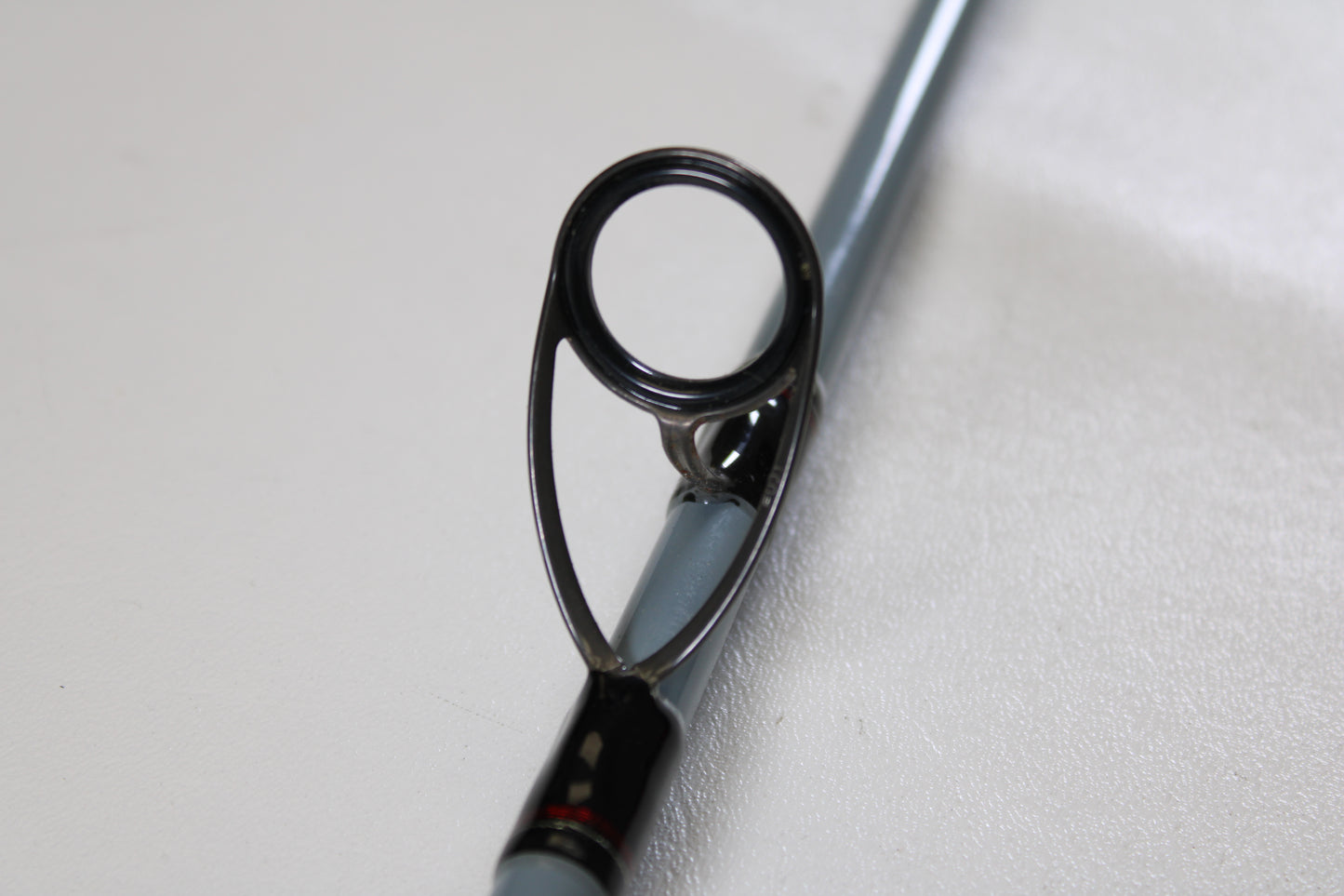 Close-up of a Daiwa Team Daiwa Surf TDSF1062MHFS 10'6" Medium Heavy 2 Piece Spinning Rod guide, showing the metal loop for directing line. Used rod in very good condition—eligible for our Rod and Reel Trade-In Program. Plain, light background.