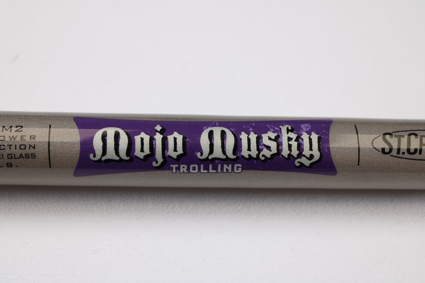 A close-up of the St. Croix Mojo Musky Trolling MMT90HM2 9'0" Heavy Used Casting Rod in mint condition, ideal for anglers seeking quality gear or trading in with our Rod and Reel Trade-In Program. The rod is shown resting on a white surface.