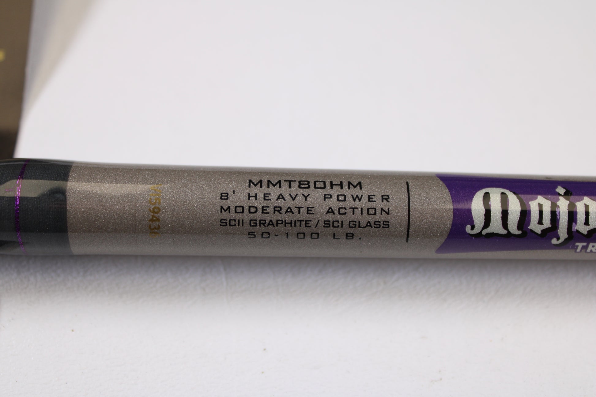 Close-up of a St. Croix Mojo Musky Trolling MMT80HM 8'0" Heavy used casting rod in mint condition, gray and purple, on a white surface—eligible for our Rod and Reel Trade-In Program for store credit.