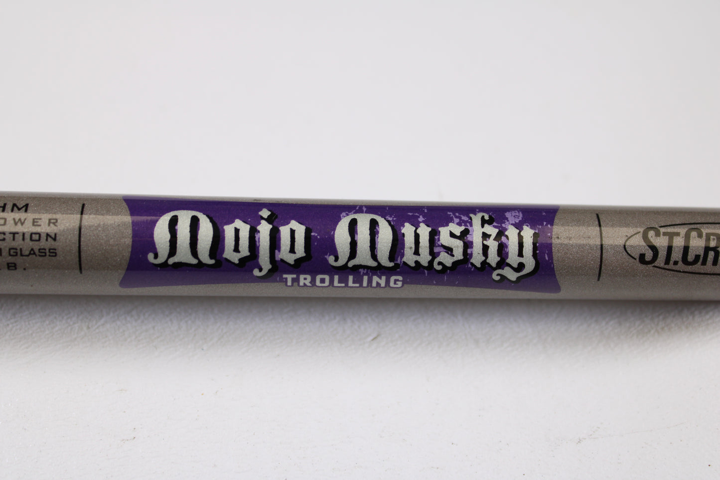 A close-up of a St. Croix Mojo Musky Trolling MMT80HM 8'0" Heavy used casting rod in mint condition features white and purple labeling on gray. Perfect for our Rod and Reel Trade-In Program, the St. Croix branding is partly visible on the right.