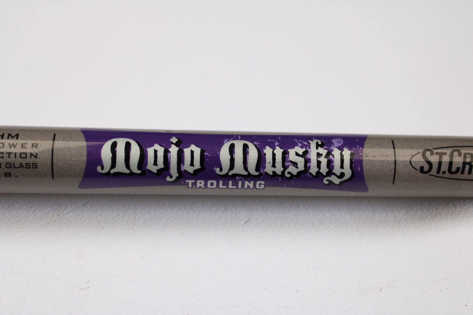 A close-up of a St. Croix Mojo Musky Trolling MMT80HM 8'0" Heavy used casting rod in mint condition features white and purple labeling on gray. Perfect for our Rod and Reel Trade-In Program, the St. Croix branding is partly visible on the right.
