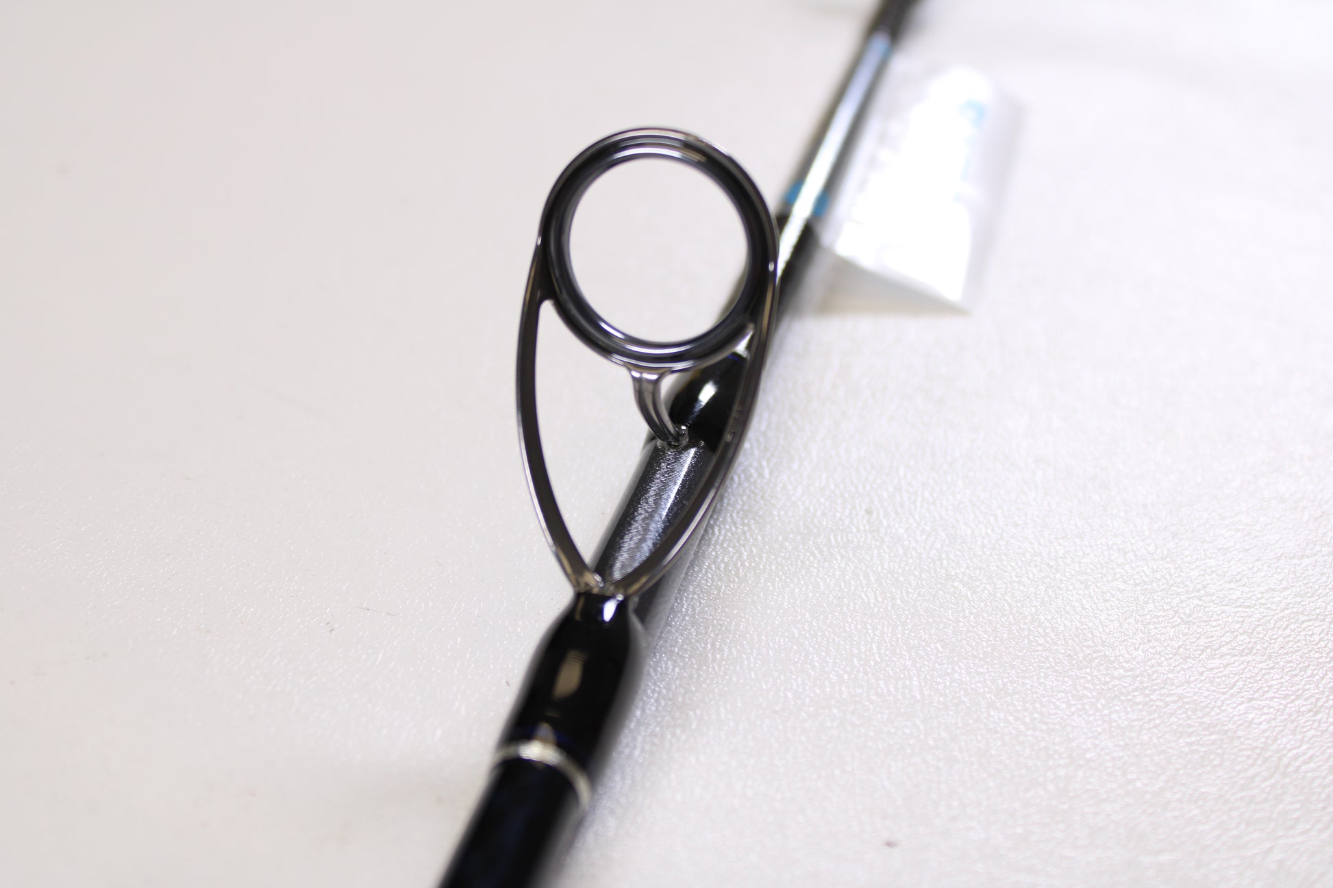 Close-up of a Shimano Terez BW TZBWS72MSBA 7'2" Medium Used Casting Rod in mint condition, highlighting the guide ring on its sleek black finish against a white background. Great option if you're considering an upgrade with our trade-in program.