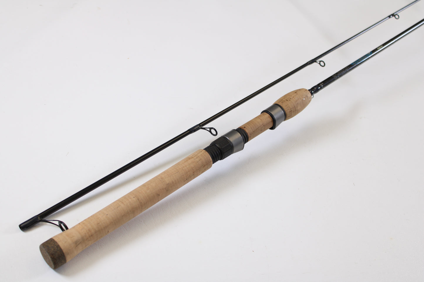 The St. Croix Avid AVS80MLM2 8'0" Medium Light 2 Piece Used Spinning Rod, in excellent condition, with a cork handle and dark metal guides, is featured diagonally on a white surface as part of our Rod and Reel Trade-In Program.