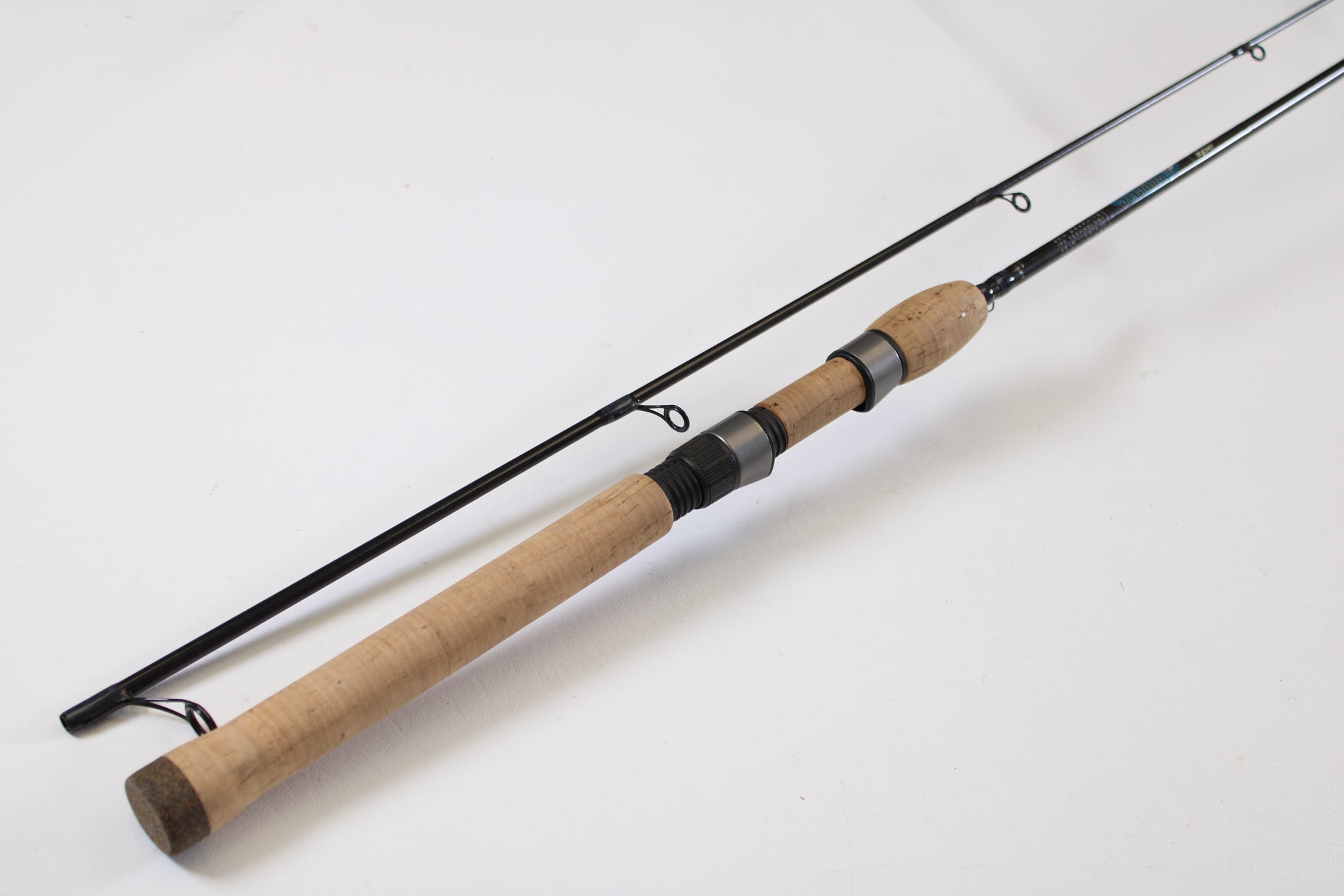 The St. Croix Avid AVS80MLM2 8'0" Medium Light 2 Piece Used Spinning Rod, in excellent condition, with a cork handle and dark metal guides, is featured diagonally on a white surface as part of our Rod and Reel Trade-In Program.