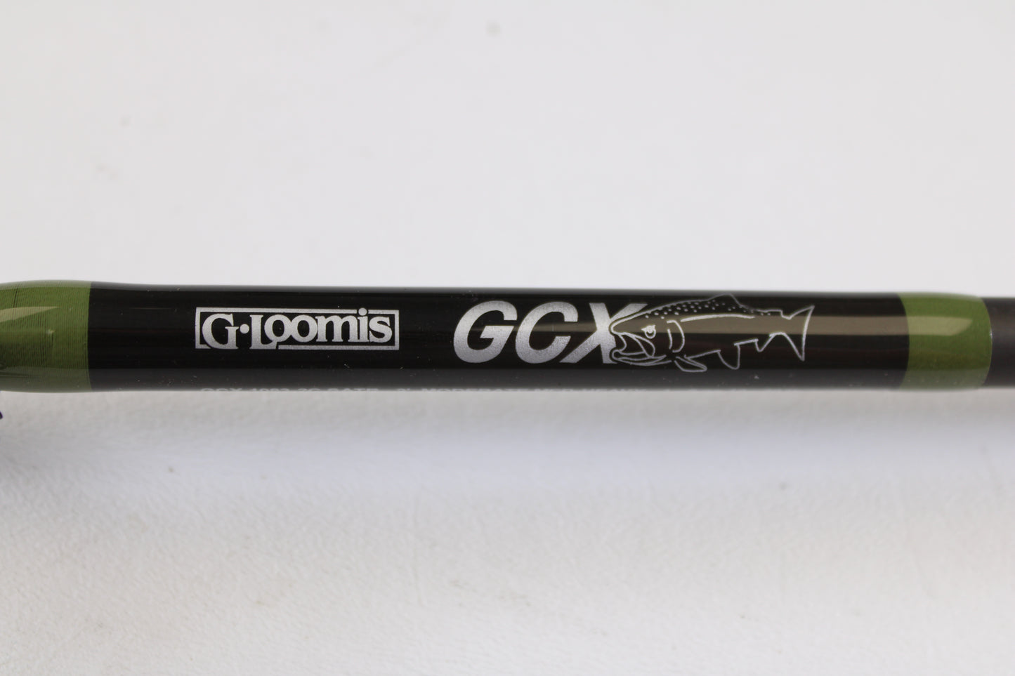 Close-up of a G. Loomis GCX Salmon 1083-2C SATR 9'0" Medium Heavy 2 Piece used casting rod in mint condition, featuring the brand logo and fish graphic—ideal for upgrades with our rod and reel trade-in program.