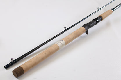 A G. Loomis Salmon & Steelhead Mooching SAMR1265C 10'6" Heavy Used Casting Rod (mint condition) with a cork handle and black reel seat is laid unassembled on a white surface, ideal for our rod and reel trade-in program.