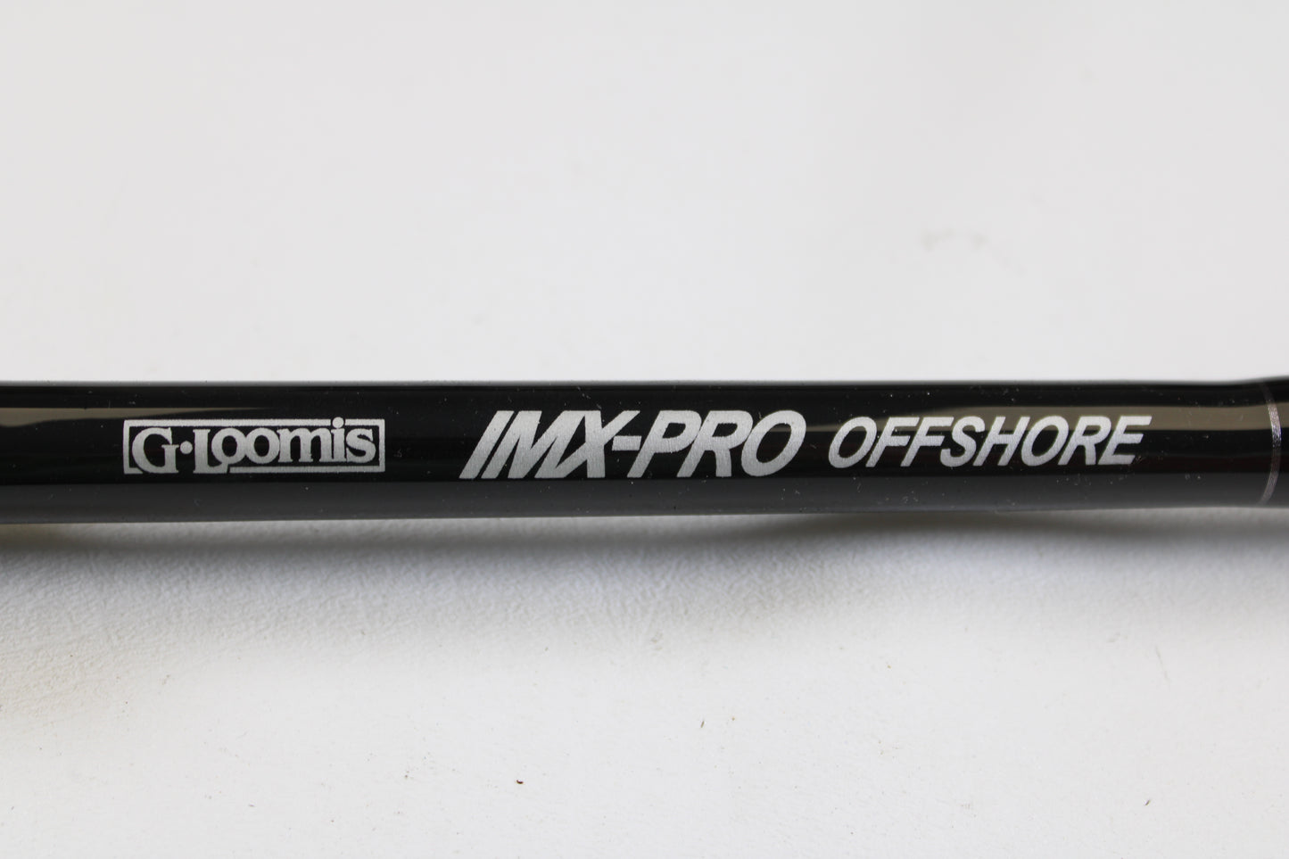 A close-up of the G. Loomis IMX-PRO Offshore 90-40 7'6" Medium Heavy Used Casting Rod in mint condition, with white "G. Loomis IMX-PRO OFFSHORE" text—ideal for those trading in rods or earning store credit with used gear.