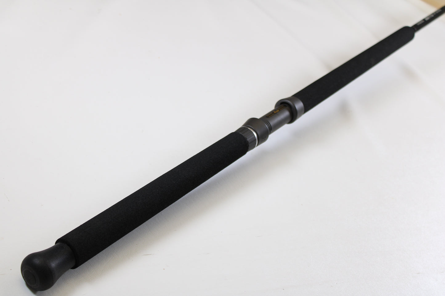 A close-up of the G. Loomis IMX-PRO Offshore 96-40 8'0" Medium Heavy Used Casting Rod, in mint condition, displays its black foam grip and reel seat—great for those interested in our rod and reel trade-in program for store credit.