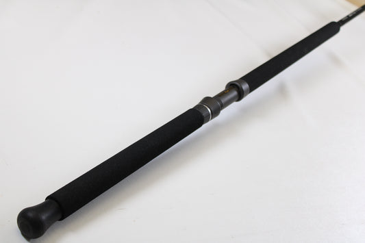 A close-up of the G. Loomis IMX-PRO Offshore 96-40 8'0" Medium Heavy Used Casting Rod, in mint condition, displays its black foam grip and reel seat—great for those interested in our rod and reel trade-in program for store credit.