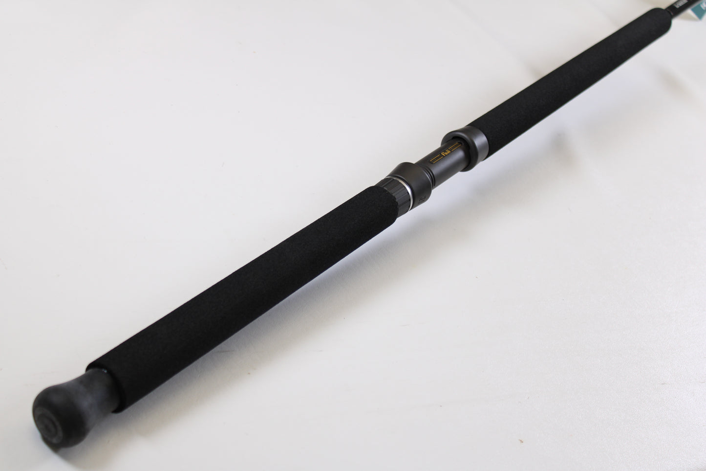 A close-up of the G. Loomis IMX-PRO Offshore 90-50 7'6" Heavy, a black used casting rod in mint condition, with foam grip and metal reel seat—ideal for anglers using our Rod and Reel Trade-In Program for store credit.