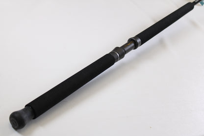 A close-up of the G. Loomis IMX-PRO Offshore 90-50 7'6" Heavy, a black used casting rod in mint condition, with foam grip and metal reel seat—ideal for anglers using our Rod and Reel Trade-In Program for store credit.