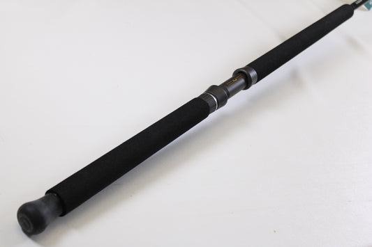 A close-up of the G. Loomis IMX-PRO Offshore 90-50 7'6" Heavy, a black used casting rod in mint condition, with foam grip and metal reel seat—ideal for anglers using our Rod and Reel Trade-In Program for store credit.
