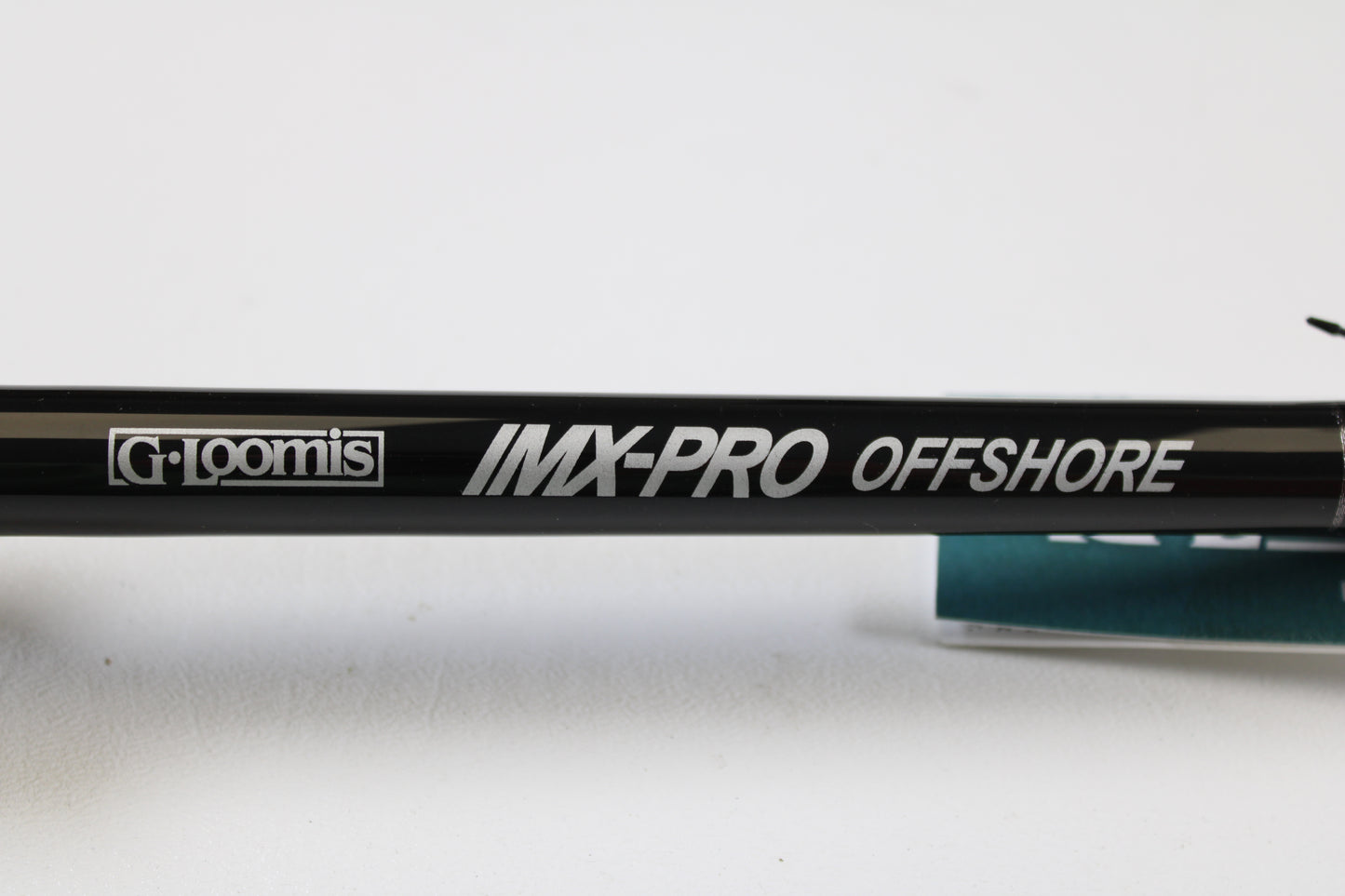 Close-up of a G. Loomis IMX-PRO Offshore 96-30 8'0" Medium Used Casting Rod in mint condition, with bold branding—eligible for our Rod and Reel Trade-In Program to turn used gear into store credit.
