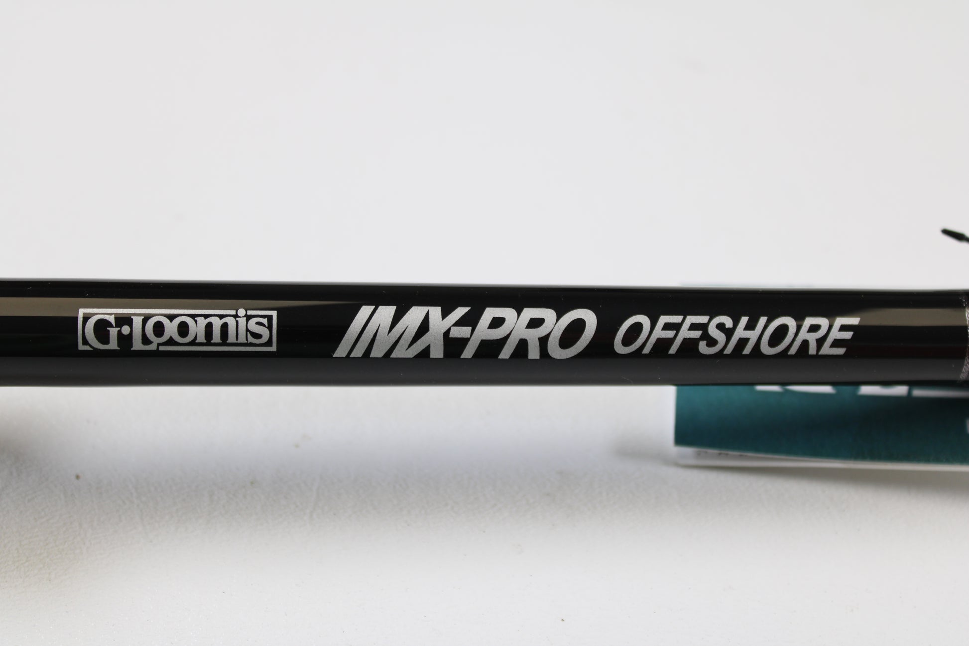 Close-up of a G. Loomis IMX-PRO Offshore 96-30 8'0" Medium Used Casting Rod in mint condition, with bold branding—eligible for our Rod and Reel Trade-In Program to turn used gear into store credit.
