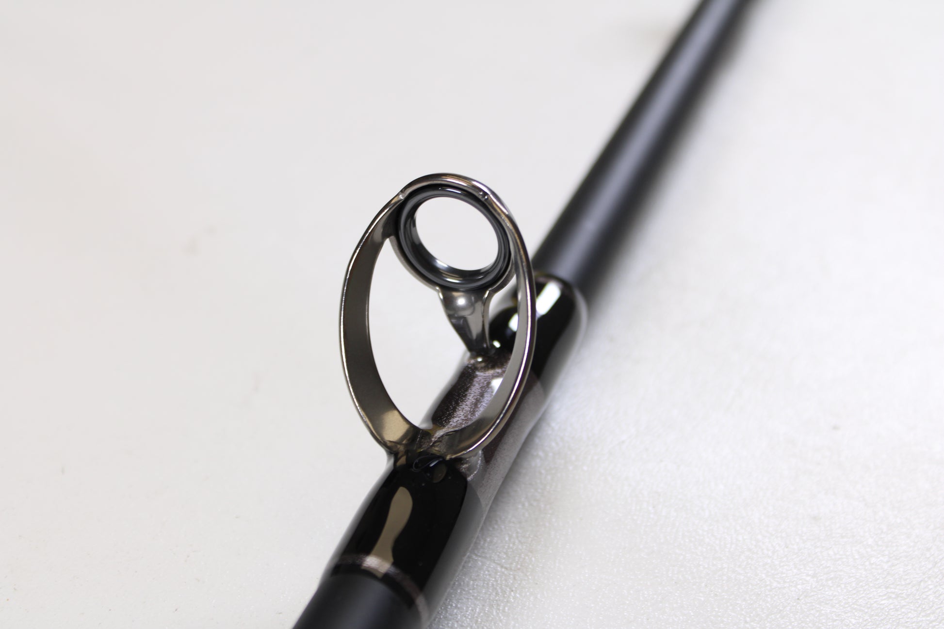 Close-up of the G. Loomis IMX-PRO Offshore 90-80 7'6" XXH—Used Casting Rod in mint condition, highlighting its glossy guide ring. Upgrade with our Rod and Reel Trade-In Program and get store credit for your used G. Loomis gear.
