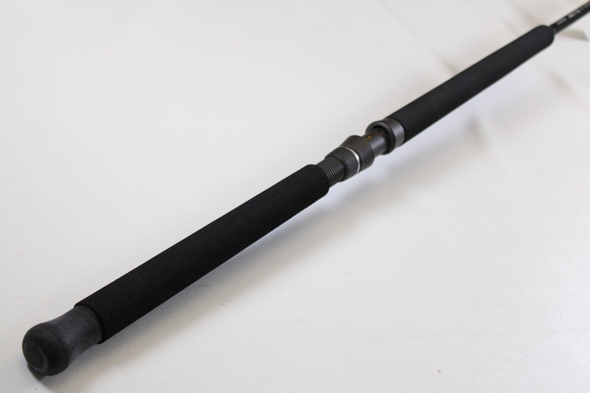 A close-up of the G. Loomis IMX-PRO Offshore 90-60 7'6" XH used casting rod in mint condition, featuring black foam grips and a metal reel seat, ideal for anglers considering pre-owned gear or a trade-in.