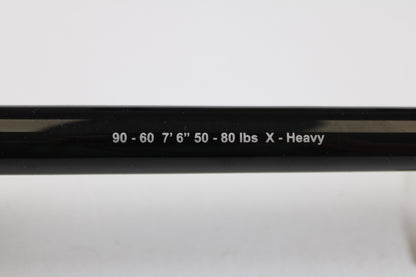 A close-up of a G. Loomis IMX-PRO Offshore 90-60 7'6" XH Used Casting Rod in mint condition, featuring white text on a black finish—ideal for trading in or earning store credit on used G. Loomis gear.