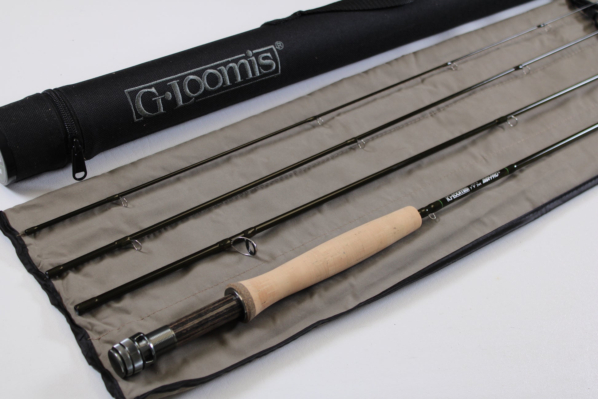 A G. Loomis IMX-PRO Creek Fly Rod 279-4 7'9" #2 with a cork handle is laid out on protective cloth beside its branded case—eligible for store credit through our Rod and Reel Trade-In Program. Mint condition, used fly rod by G. Loomis.