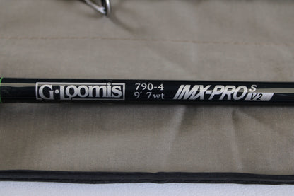 Close-up of a G. Loomis IMX-PRO V2S Saltwater 790-4 9'0" #7 used fly rod in mint condition on beige fabric—ideal for anglers looking to trade in or upgrade their gear for store credit.