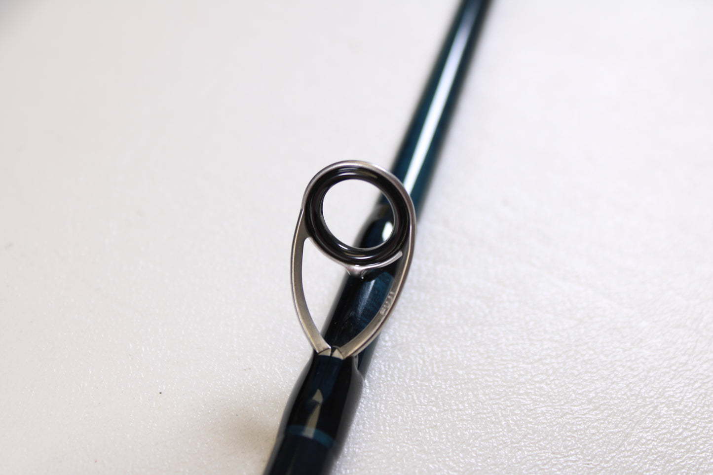 Close-up of the G. Loomis IMX-PRO V2S Saltwater 790-4 9'0" #7—Used Fly Rod in mint condition, highlighting a single metal guide ring against a white background—ideal for our rod and reel trade-in program.