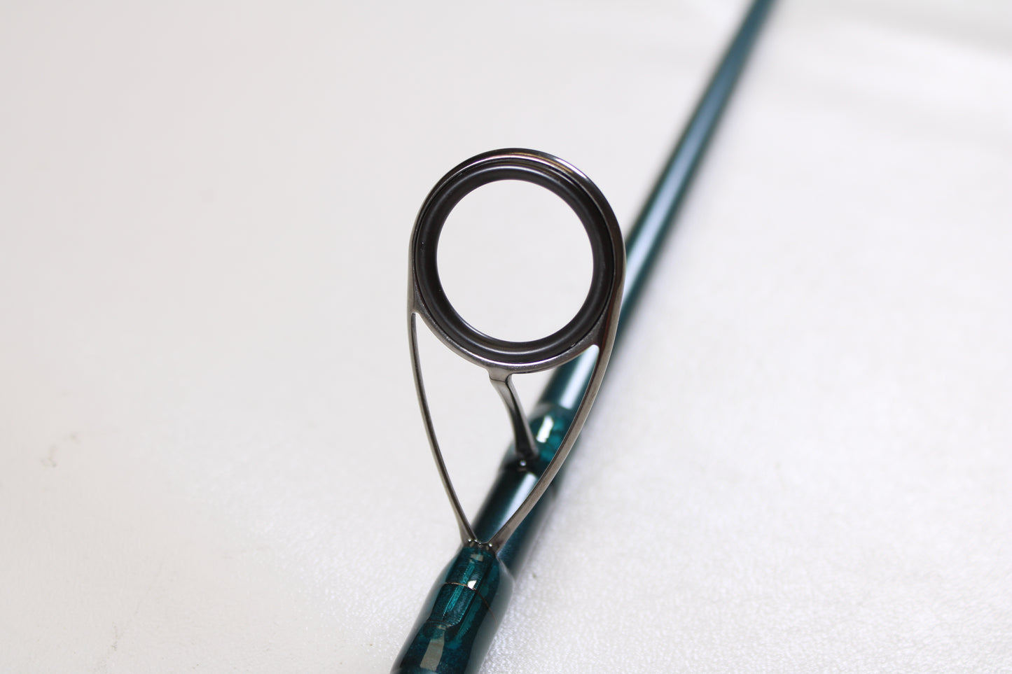 Close-up of a St. Croix Mojo Inshore JIS66HF 6'6" Heavy Used Spinning Rod in mint condition, highlighting the guide ring—ideal for anglers trading in gear with our Rod and Reel Trade-In Program. Out-of-focus rod on white background.