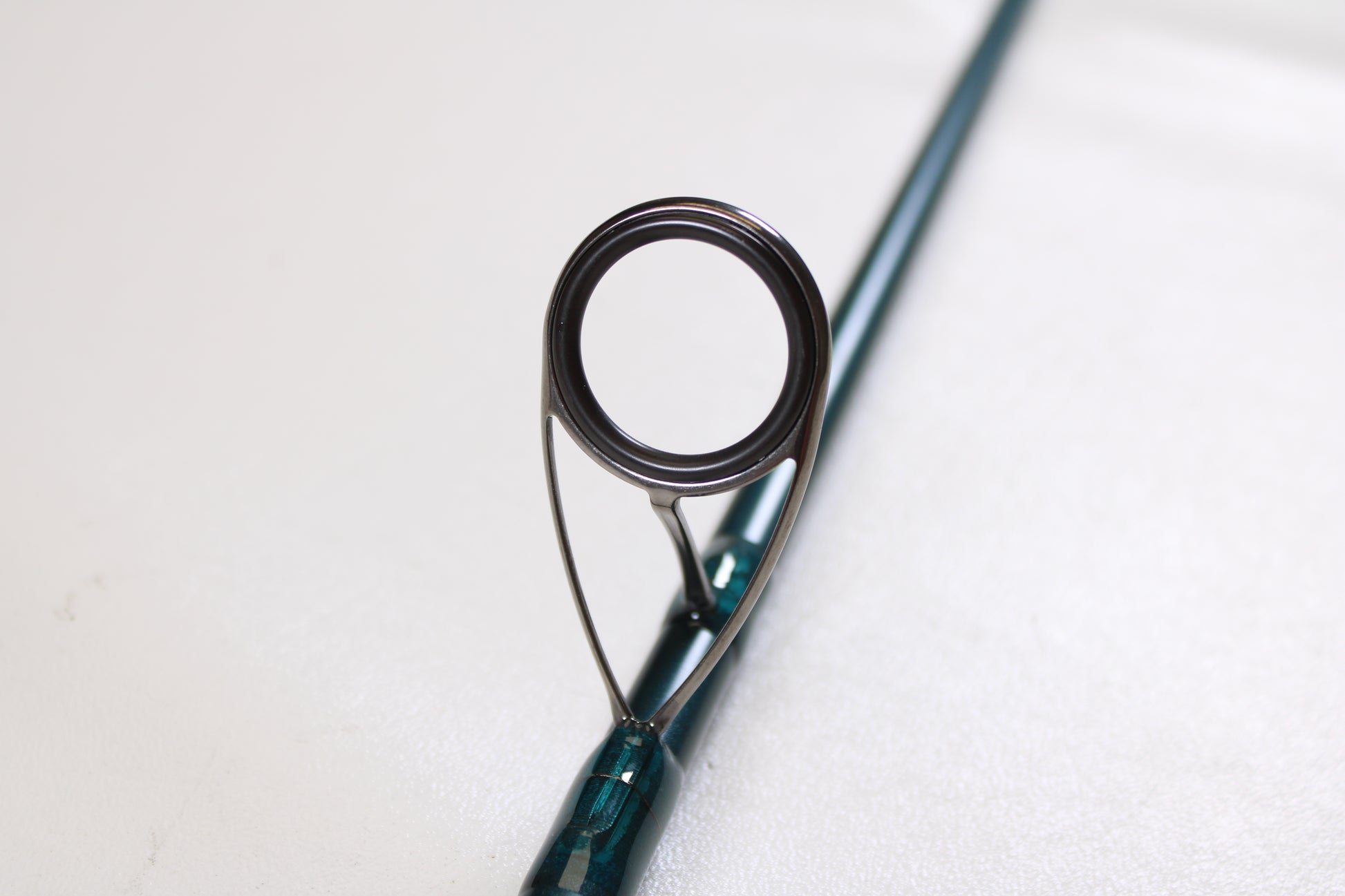 Close-up of a St. Croix Mojo Inshore JIS66HF 6'6" Heavy Used Spinning Rod in mint condition, highlighting the guide ring—ideal for anglers trading in gear with our Rod and Reel Trade-In Program. Out-of-focus rod on white background.