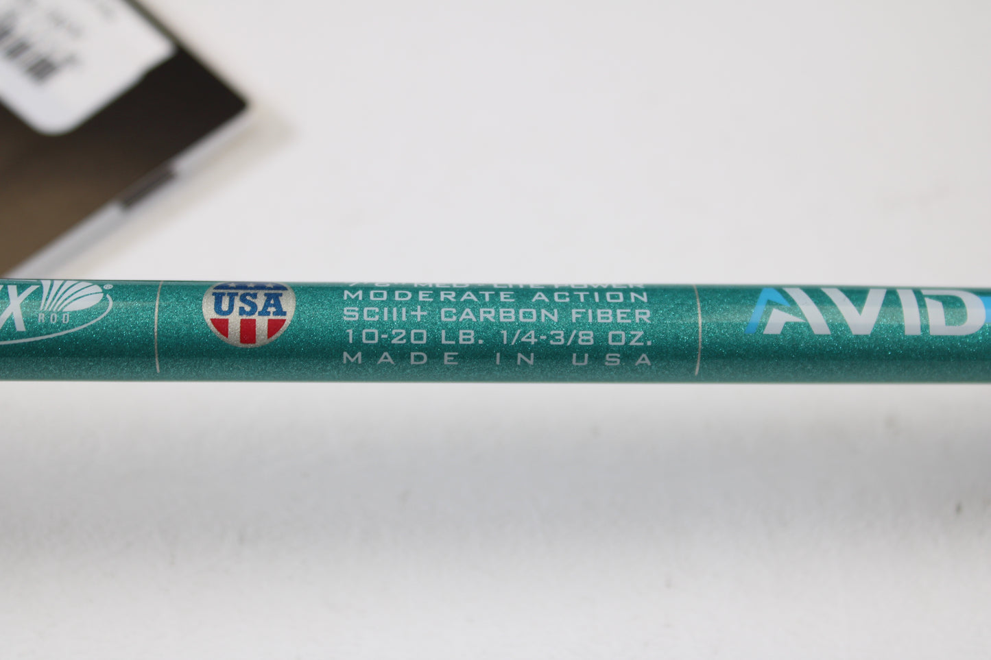 A close-up of a St. Croix Avid Inshore ASIC76MLM 7'6" Medium Light casting rod (used, mint), showing text: "Moderate Action, SCIII+ Carbon Fiber, 10-20 lb, 1/4-3/8 oz, Made in USA"—eligible for rod and reel trade-in for store credit.