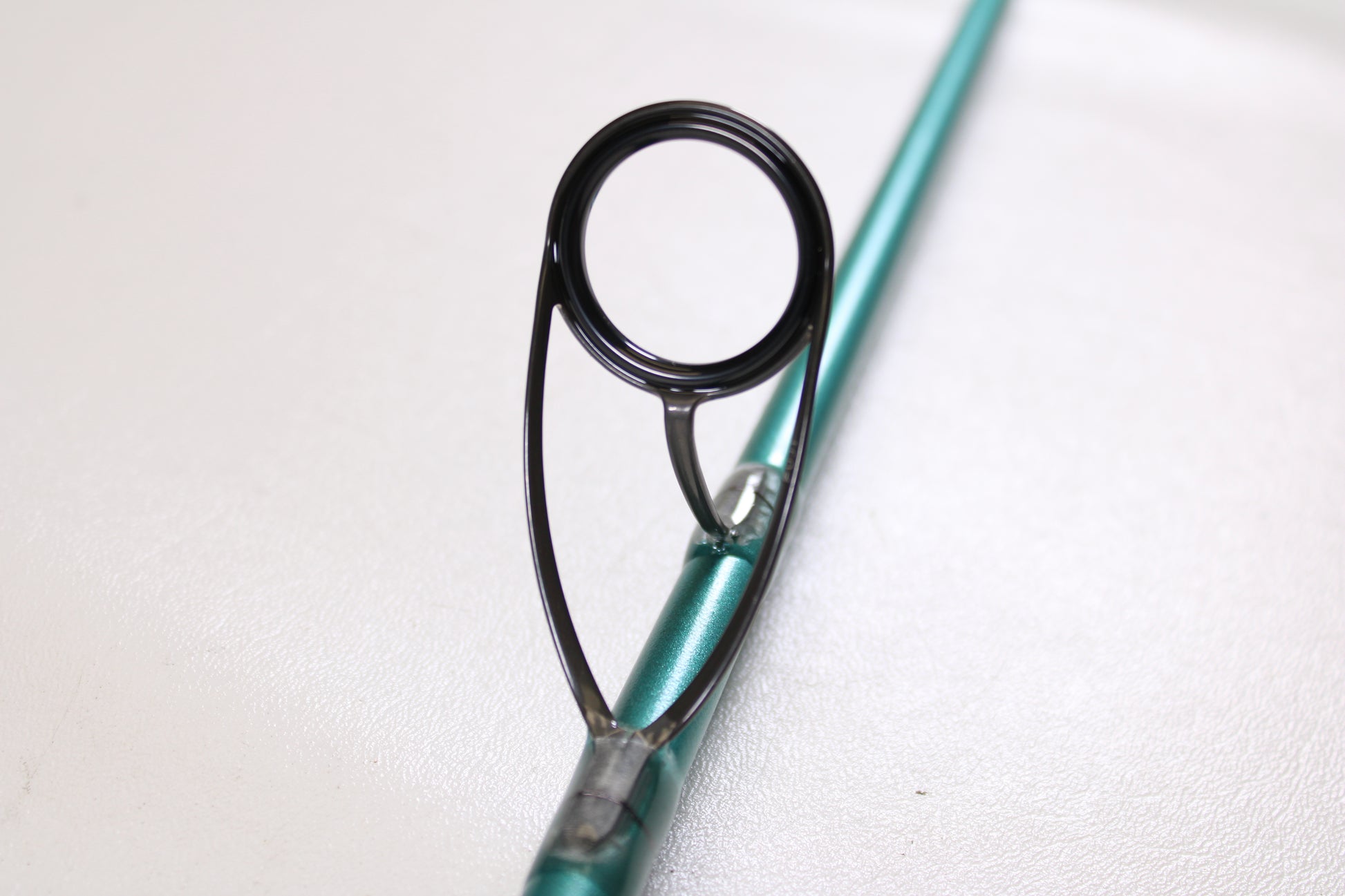 Close-up of a St. Croix Avid Inshore ASIS70HMF 7'0" Heavy Used Spinning Rod in mint condition, highlighting the metallic guide on a teal rod—ideal for those interested in premium used gear or our trade-in program.