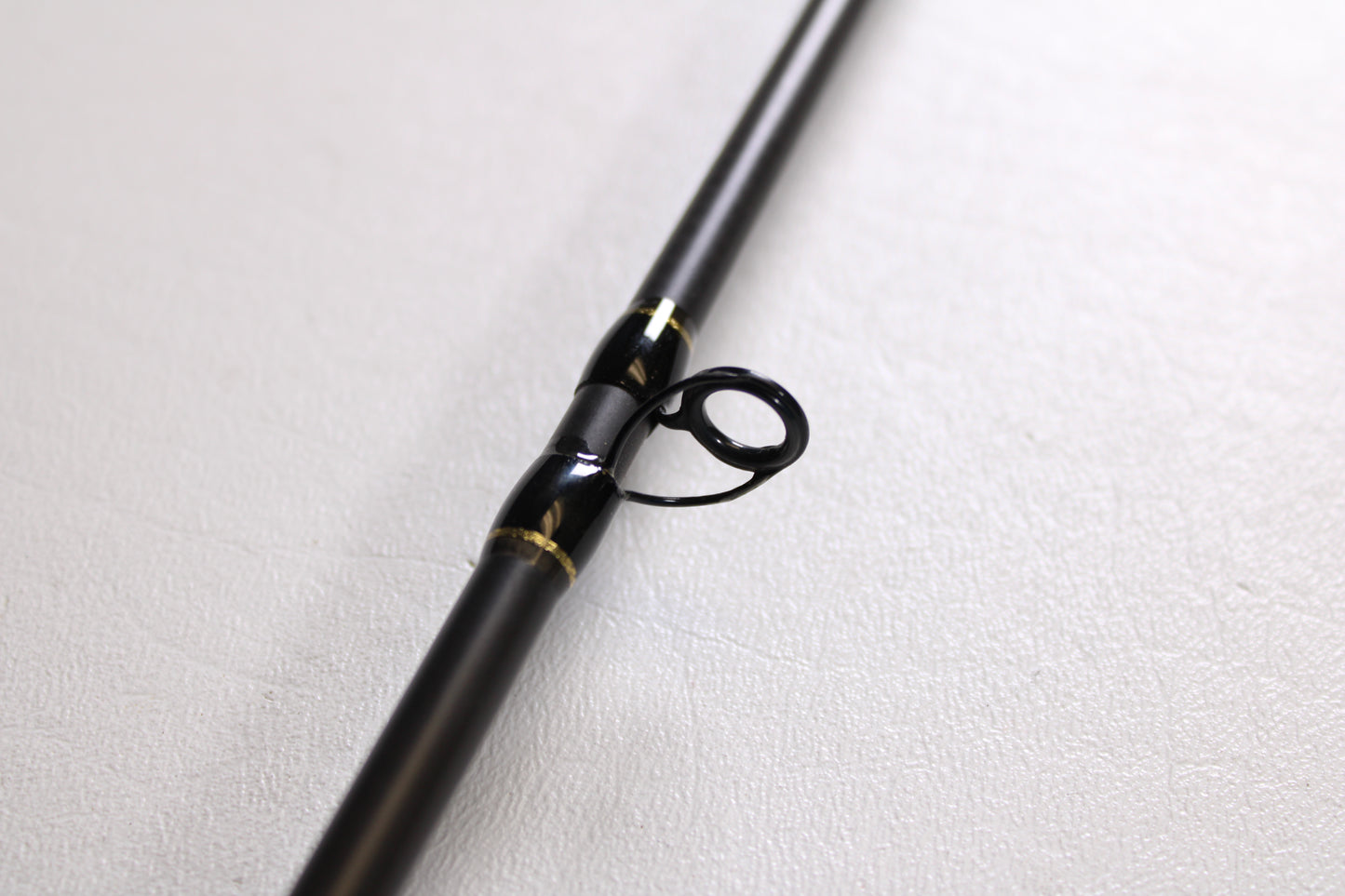 A close-up of the Falcon Cara T7 CC-4-166M 6'6" Medium used casting rod in very good condition, featuring a black body with metal line guide and gold accents—ideal for anyone seeking quality pre-owned Falcon gear.