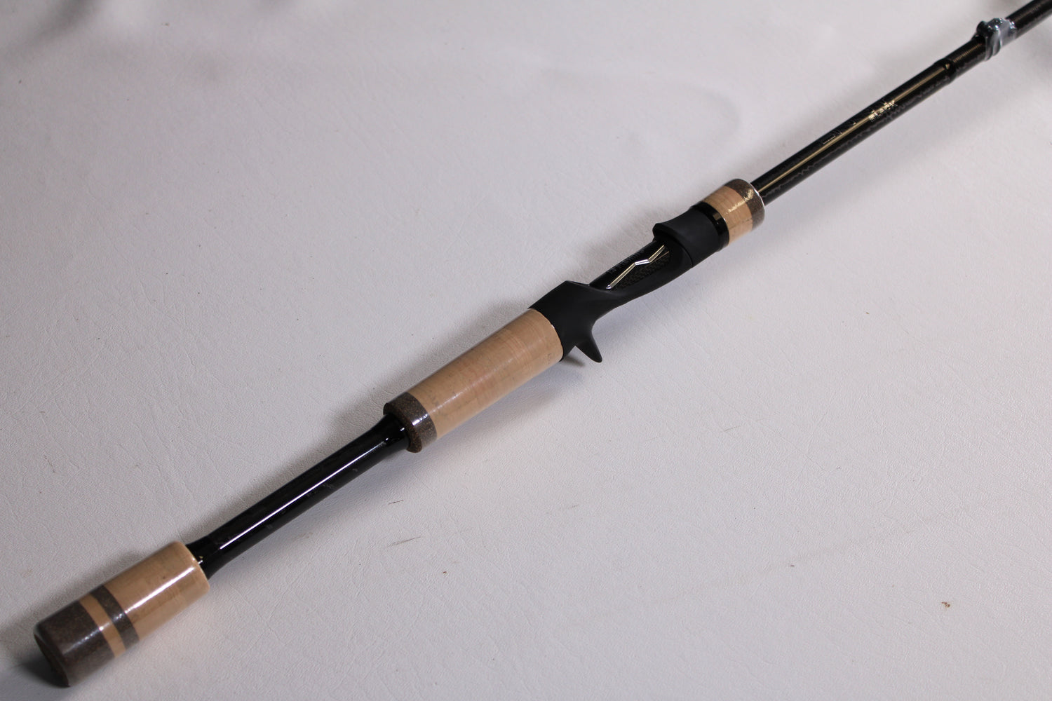 A close-up of the 13 Fishing Envy Black 3 EB3C76MH 7'6" Medium Heavy Casting Rod—used, mint condition—on a plain white surface; ideal for upgrading through our rod and reel trade-in or shopping quality used fishing gear.