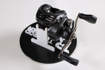 A Lew's Speed Spool SS1HLA 6.8:1 LH casting reel in very good used condition is shown with dual handles on a black and white circular stand, ideal for upgrading your gear or trading in through our Rod and Reel Trade-In Program.
