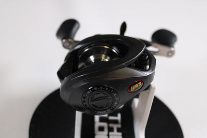 A Lew's Speed Spool SS1HLA 6.8:1 LH used casting reel in very good condition is shown on a white stand with adjustment dials, handle grips, and the Lew's logo, featured as part of our Rod and Reel Trade-In Program.