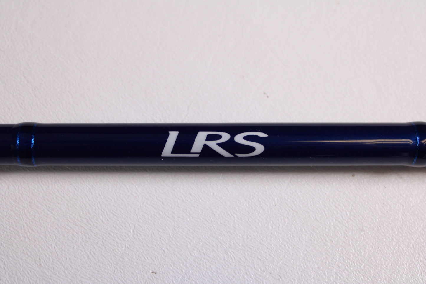 A Douglas LRS LRSC784F 7'8" Medium Used Casting Rod in excellent condition, dark blue with "LRS" lettering, shown on a white surface—may be eligible for store credit through our rod and reel trade-in program.