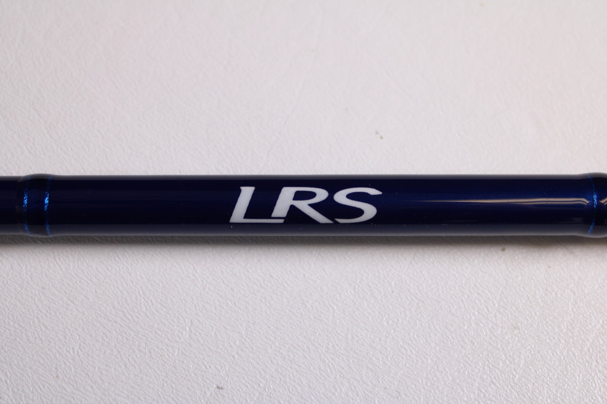 A Douglas LRS LRSC784F 7'8" Medium Used Casting Rod in excellent condition, dark blue with "LRS" lettering, shown on a white surface—may be eligible for store credit through our rod and reel trade-in program.