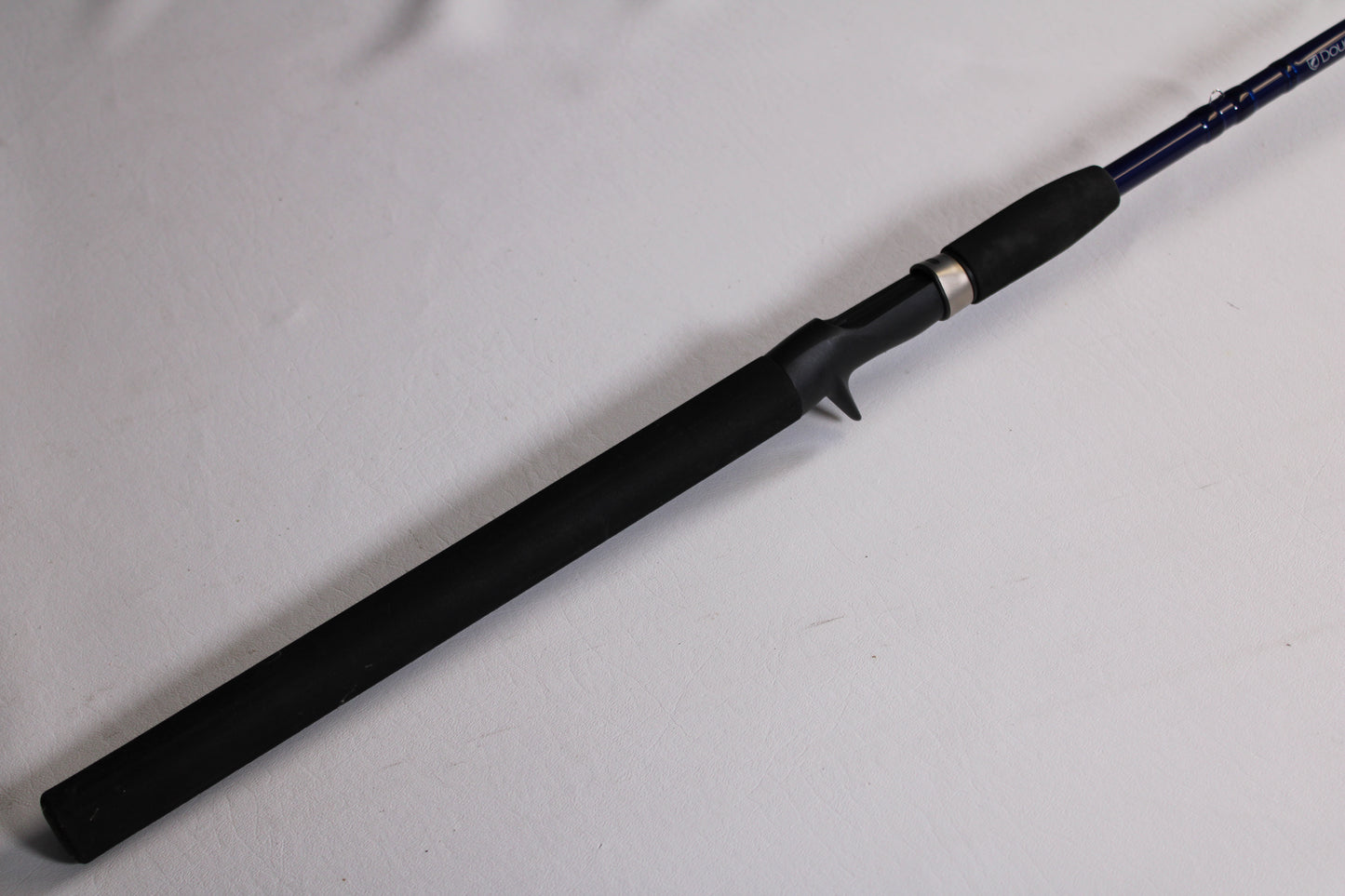 A close-up of the Douglas LRS LRSC7115F 7'11" Heavy used casting rod in excellent condition shows its black grip and trigger-style reel seat—ideal for those looking to trade in gear for store credit.