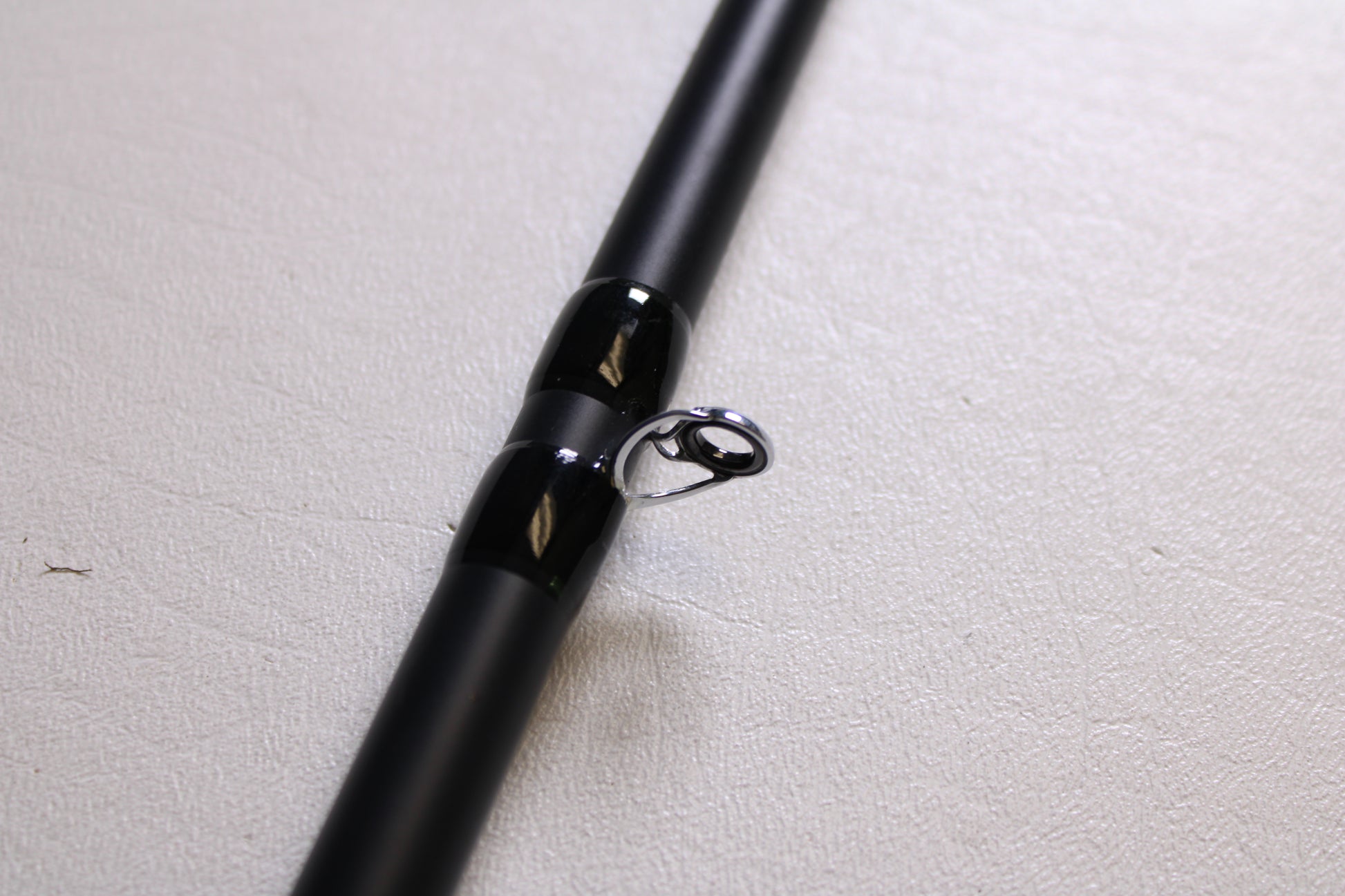 Close-up of the Fitzgerald Titan HD THD76H 7'6" Heavy - Used Casting Rod in very good condition, featuring a shiny silver guide ring—upgrade through our Rod and Reel Trade-In Program and earn store credit for your used Fitzgerald gear.
