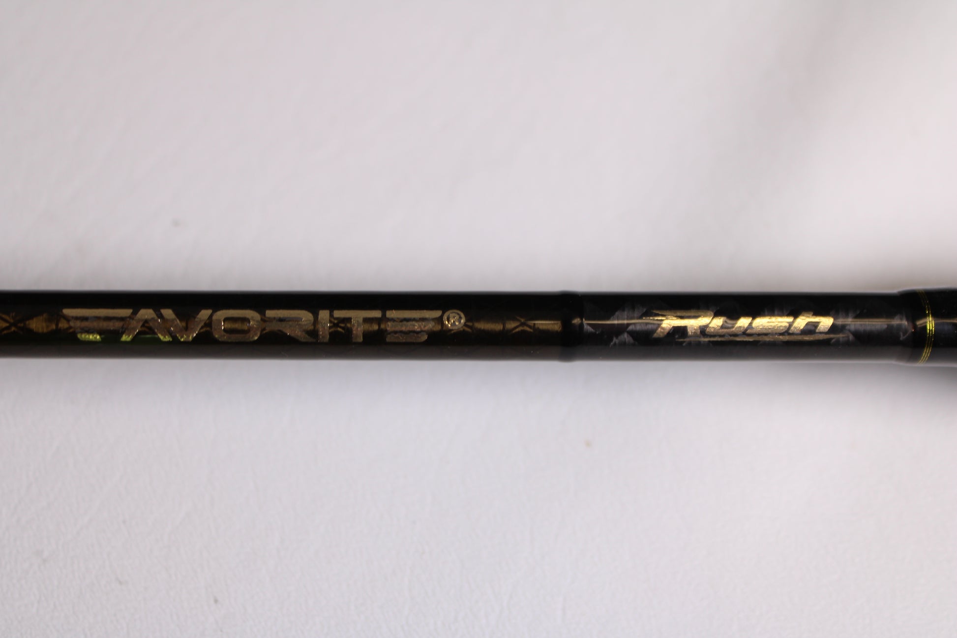A close-up of the Favorite Fishing Rush RUH-661MH 6'6" Medium Heavy used spinning rod in mint condition, with "Favorite Fishing" and "Rush" in gold lettering, perfect for upgrading your fishing gear or adding to your collection.
