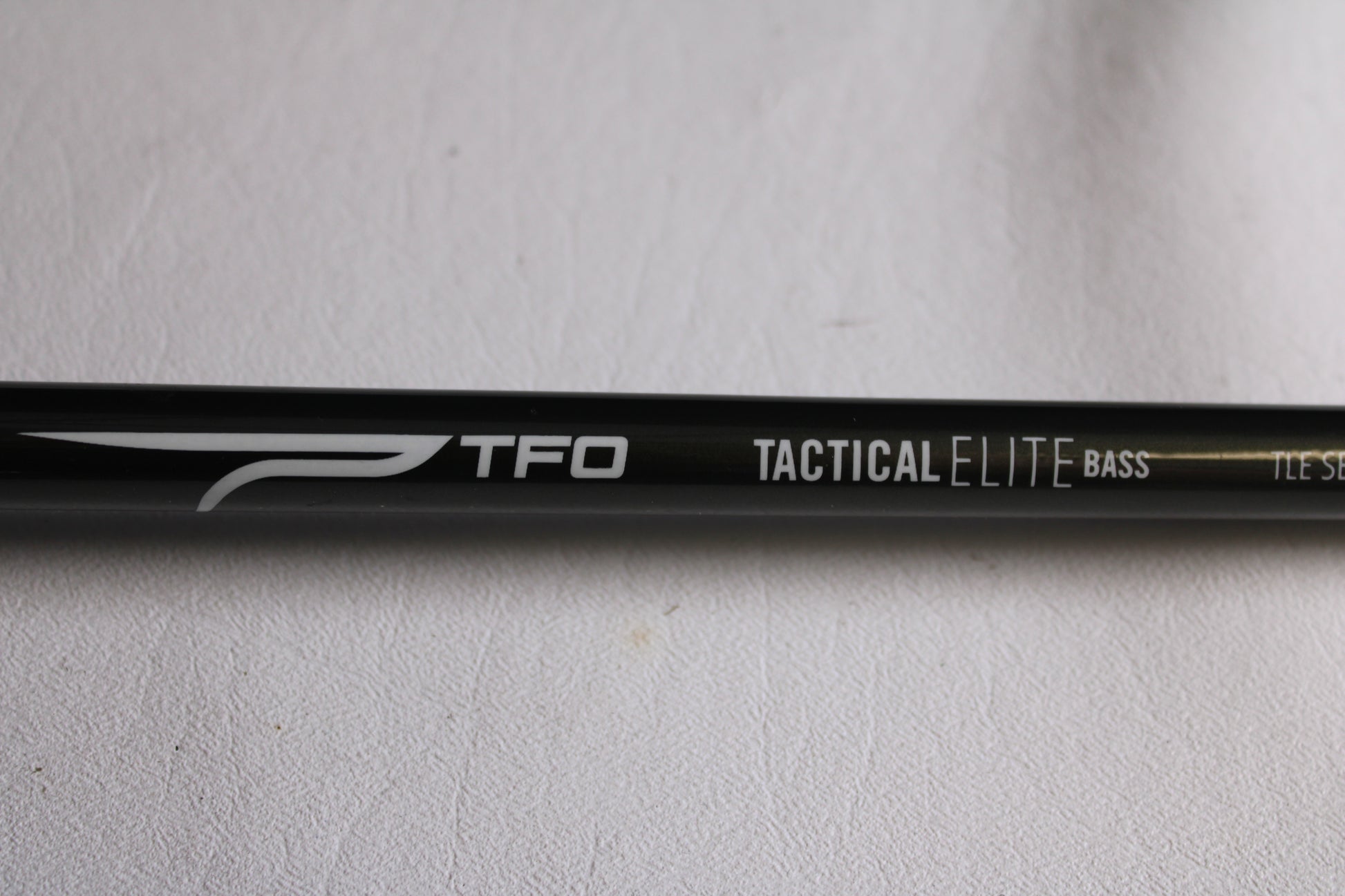 Close-up of a Temple Fork TFO Tactical Elite Bass TLE SB 726-1 7'2" Heavy Used Casting Rod (Excellent Condition) with white text on black—ideal for anglers seeking an upgrade through our rod and reel trade-in program.