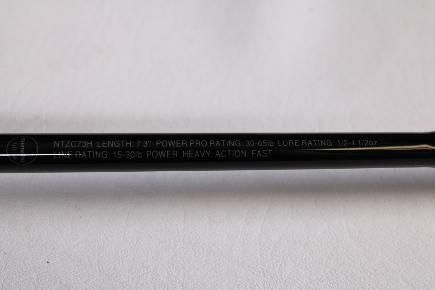 A close-up of the Shimano Intenza NTZC73H 7'3" Heavy Used Casting Rod in mint condition, ideal for our trade-in program. Specs: 30-65lb PowerPro, 1/2–1 1/2oz lure rating, 15-30lb line rating; heavy action, fast power.