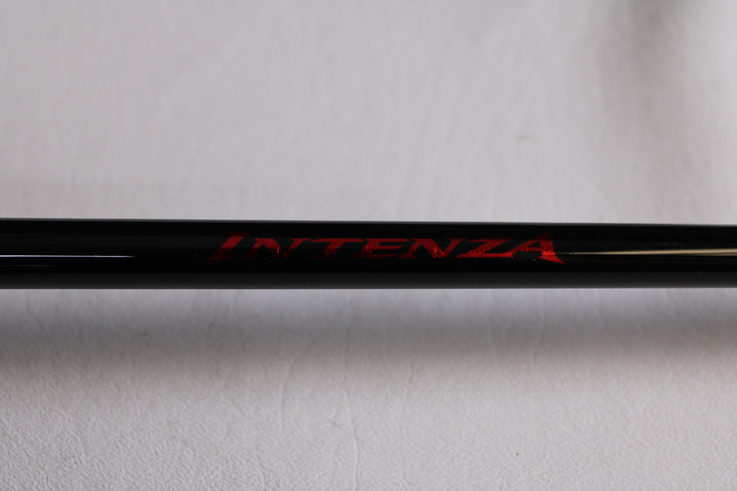 Close-up of a Shimano Intenza NTZC73H 7'3" Heavy used casting rod in mint condition, placed on a light gray background—perfect for anglers upgrading gear through our trade-in program to earn store credit.