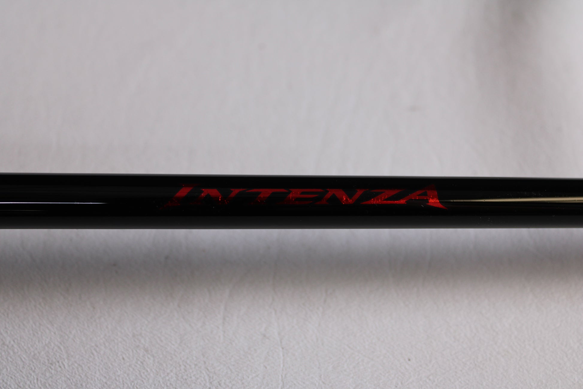 Close-up of a Shimano Intenza NTZC73H 7'3" Heavy used casting rod in mint condition, placed on a light gray background—perfect for anglers upgrading gear through our trade-in program to earn store credit.
