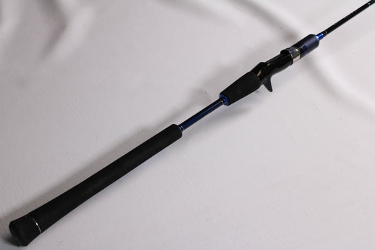 A close-up of a Shimano Game Type J B60-5 6'0" Used Casting Rod in excellent condition, featuring a black handle and blue accents on a white surface. Ideal for used gear enthusiasts or our Rod and Reel Trade-In Program for store credit.