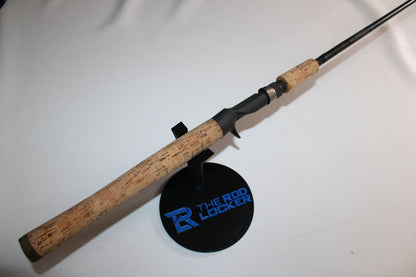A St. Croix Premier PC66MF Used Casting Rod in good condition with a cork handle is displayed diagonally on a black stand labeled "THE ROD LOCKER" in blue, set against a plain white background.