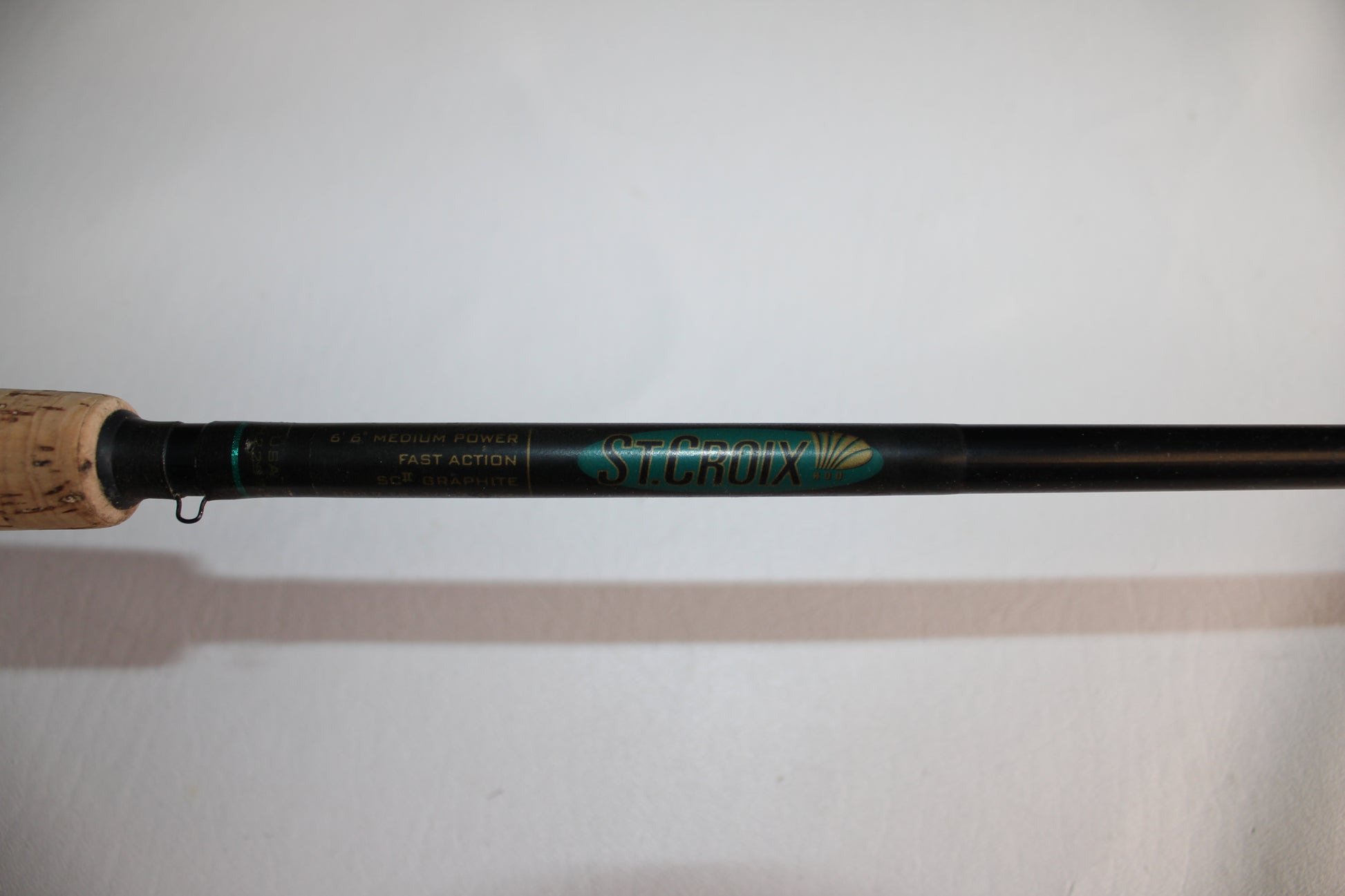 Close-up of the St. Croix Premier PC66MF Used Casting Rod in good condition, showing its cork handle and label with specifications on a white background.