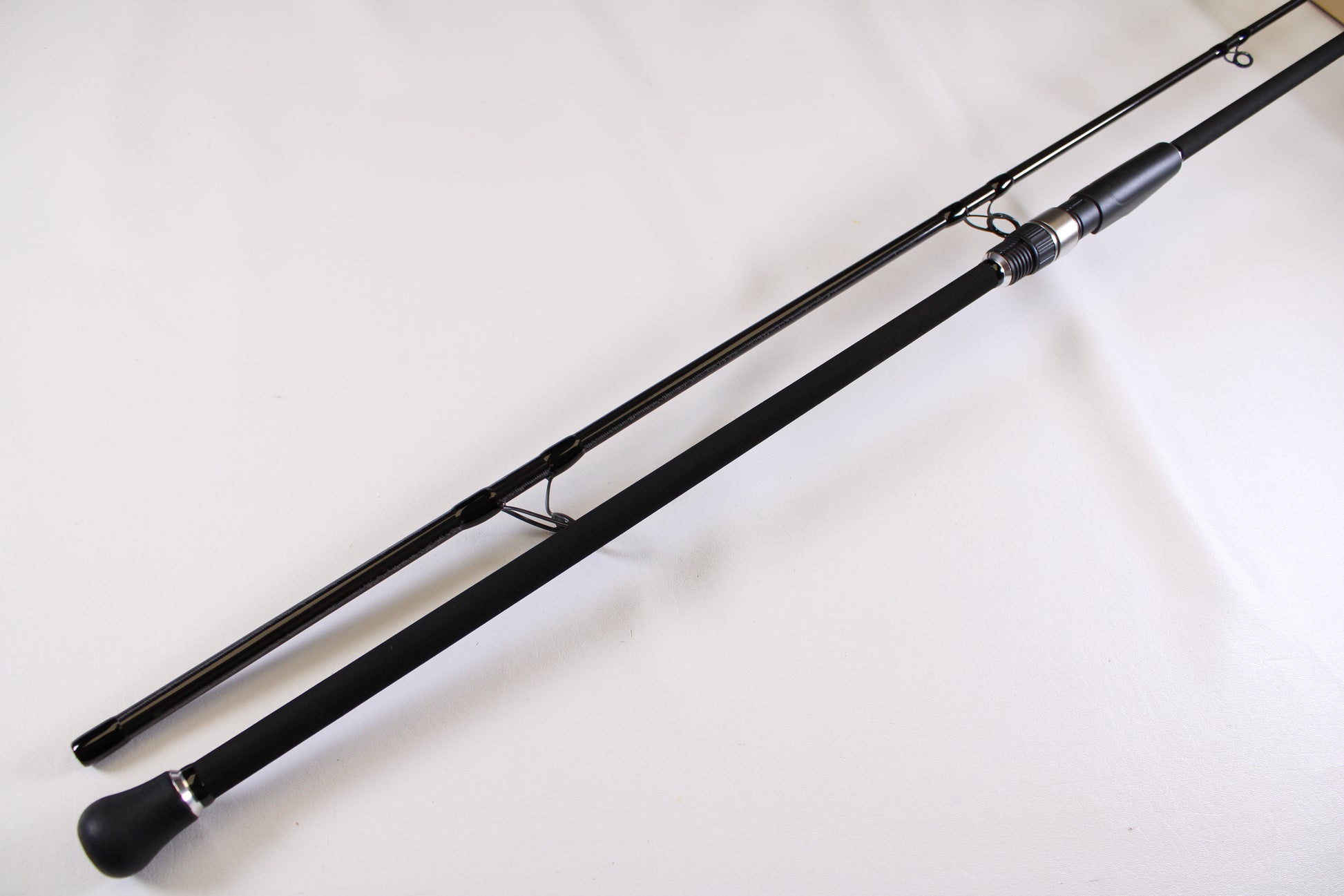 A close-up of an ODM Rods Genesis Surf NGX-114 11'0" 2-piece used spinning rod in excellent condition with metal guides and a foam handle, ideal for anyone interested in quality pre-owned fishing gear or trade-ins.
